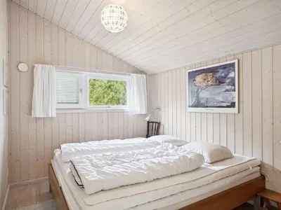 a white bedroom with a large bed with a window at Holiday Home Sigbritt - 2-6km from the sea by Interhome in Blokhus