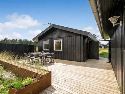 a backyard with a wooden deck and a black shed at Holiday Home Anbritt - 1km from the sea by Interhome in Saltum