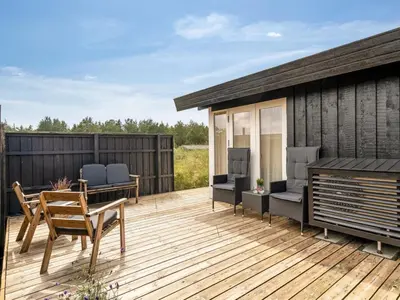 a wooden deck with chairs and a building at Holiday Home Anbritt - 1km from the sea by Interhome in Saltum
