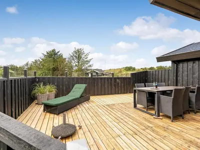 a wooden deck with a table and chairs on it at Holiday Home Anbritt - 1km from the sea by Interhome in Saltum