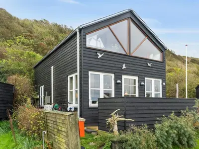 a black house with large windows on a hill at Holiday Home Benni - 75m to the fjord by Interhome in Løgstør