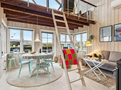 a living room with a loft bed and a table and chairs at Holiday Home Benni - 75m to the fjord by Interhome in Løgstør