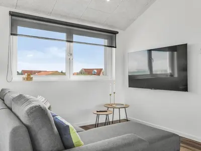 a living room with a couch and a window at Holiday Home Unge - 75m from the sea by Interhome in Torsted