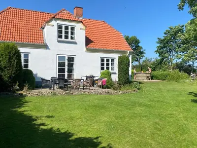 a white house with a table and chairs in the yard at Søbugten in Nykøbing Mors