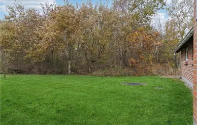 a yard with green grass and trees and a brick building at Lovely Home In Hurup Thy With Wifi in Sønder Ydby
