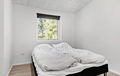 an unmade bed in a white room with a window at 3 Bedroom Cozy Home In Farsø in Farsø