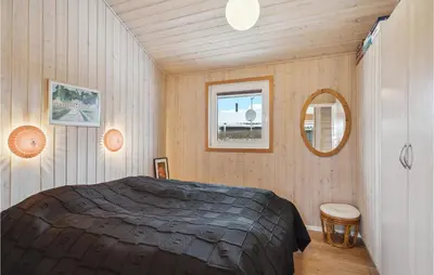 a bedroom with a large bed and a mirror at Beautiful Home In Vinderup With Sauna in Vinderup
