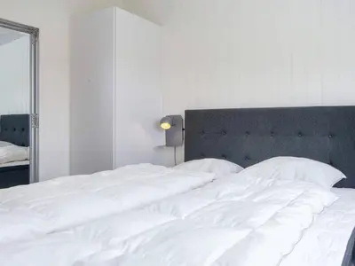 a large white bed in a bedroom with a mirror at 5 star holiday home in Lemvig-By Traum in Lemvig