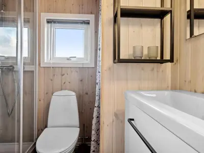 a bathroom with a toilet and a sink and a window at Holiday Home Bruni - 400m from the sea by Interhome in Frøstrup