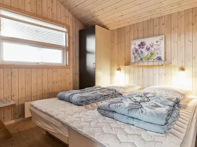 two beds in a room with wooden walls and a window at Holiday Home Bruni - 400m from the sea by Interhome in Frøstrup
