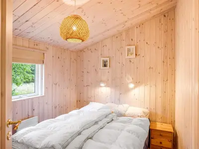 a bedroom with a large bed in a wooden wall at Holiday Home Thrineke - 600m from the sea by Interhome in Saltum
