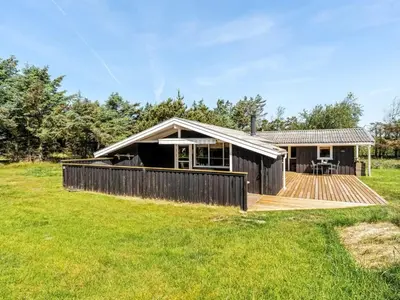 a house with a wooden deck in a field at Holiday Home Thrineke - 600m from the sea by Interhome in Saltum