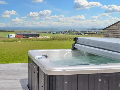 a hot tub on a deck with a view of a field at 5 star holiday home in Lemvig-By Traum in Lemvig
