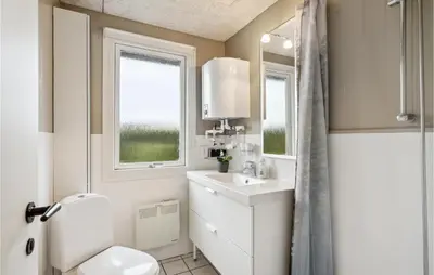 a bathroom with a toilet and a sink and a window at 4 Bedroom Cozy Home In Vinderup in Vinderup