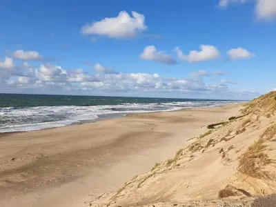 a sandy beach with the ocean on a cloudy day at 6 person holiday home in Thisted-By Traum in Thisted