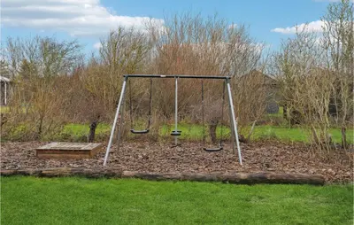 a swing set with a bench in a park at Cozy Home In Vestervig With Sauna in Vestervig