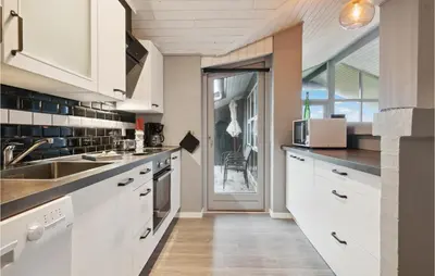 a kitchen with white cabinets and a large window at Cozy Home In Vestervig With Sauna in Vestervig