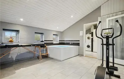 a gym with a tub and a treadmill at Cozy Home In Vestervig With Sauna in Vestervig