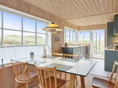 a kitchen with a table and chairs and windows at Holiday Home Merina - 150m from the sea by Interhome in Løkken