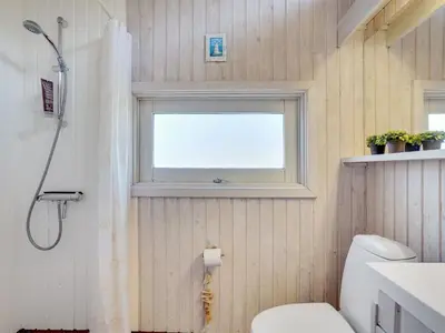 a bathroom with a shower and a toilet and a window at Holiday Home Nikodina - 200m from the sea by Interhome in Saltum