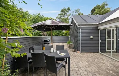 a patio with a table and an umbrella at Amazing Home In Farsø With Sauna in Farsø