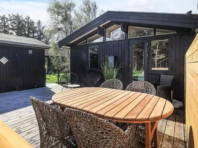 a wooden table and chairs on a deck with a house at Tranquil Beach Retreat - By Traum Ferienwohnungen in Løkken