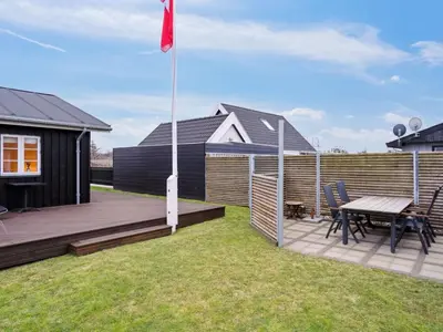a backyard with a wooden deck and a picnic table at Holiday Home Svante - 600m from the sea by Interhome in Blokhus