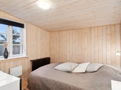 a bedroom with a bed in a wooden room at Holiday Home Svante - 600m from the sea by Interhome in Blokhus