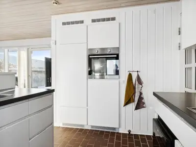 a kitchen with white cabinets and a door with a microwave at Holiday Home Leny - 900m from the sea by Interhome in Pandrup