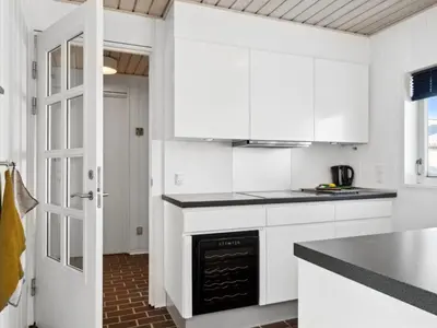 a white kitchen with white cabinets and a stove at Holiday Home Leny - 900m from the sea by Interhome in Pandrup