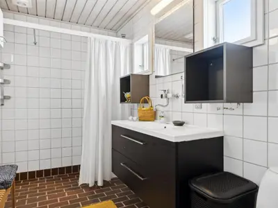 a bathroom with a sink and a television in it at Holiday Home Leny - 900m from the sea by Interhome in Pandrup