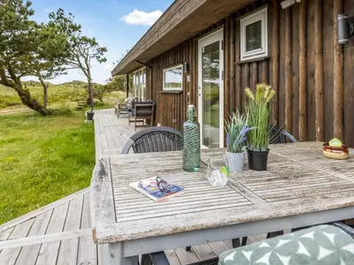 a wooden table on the deck of a house at Holiday Home Lagho - 500m from the sea by Interhome in Pandrup