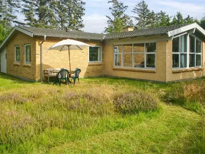 a house with a table and an umbrella in the yard at Holiday Home Gisa - 400m from the sea by Interhome in Fjerritslev