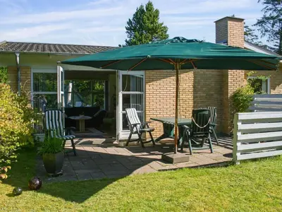 a patio with a table and chairs under an umbrella at Holiday Home Gisa - 400m from the sea by Interhome in Fjerritslev