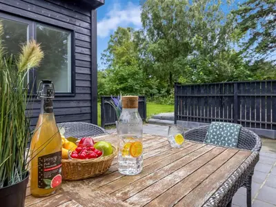 a wooden table with two bottles and a basket of fruit at Holiday Home Scalli - 1-5km to the fjord by Interhome in Farsø