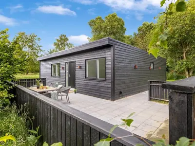 a small black tiny house with a deck at Holiday Home Scalli - 1-5km to the fjord by Interhome in Farsø