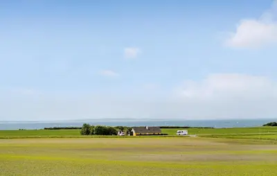 a house in a field with the ocean in the background at Nice Home In Thyholm With Wifi in Thyholm