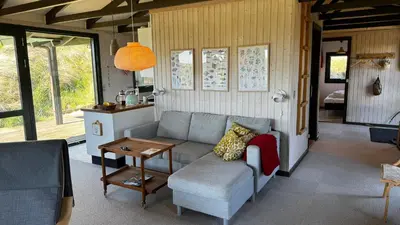 a living room with a couch and a table at Veludstyret sommerhus i unik natur 350 m fra lækker badestrand - helårsbolig in Saltum