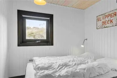 a white bed in a room with a window at Veludstyret sommerhus i unik natur 350 m fra lækker badestrand - helårsbolig in Saltum