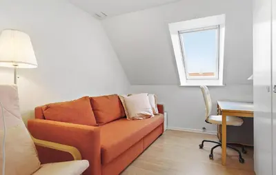 an orange couch in a room with a desk and a window at Gorgeous Home In Løgstør in Løgstør
