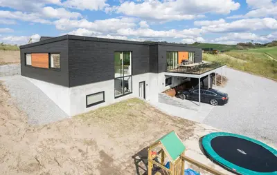 a black and white house with a car parked in the driveway at Stunning Home In Løgstrup With Kitchen in Løgstrup