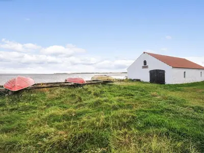 a white building and some boats in a field at Holiday Home Mirja - 50m to the fjord by Interhome in Fur