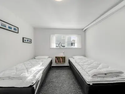 two beds in a white room with a window at Holiday Home Ullakarin - 200m from the sea by Interhome in Thyborøn