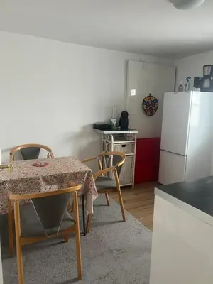 a kitchen with a table and a white refrigerator at Nice small house 5 minutes to the sea in Ranum