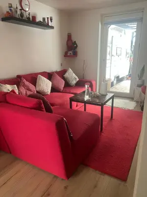 a red couch in a living room with a red rug at Nice small house 5 minutes to the sea in Ranum