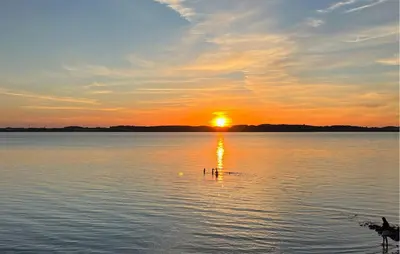 a sunset on a lake with a bird in the water at Amazing Home In Roslev With Sauna in Roslev