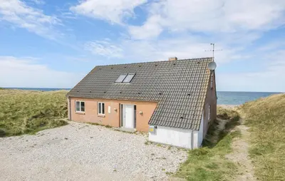 a small house on the side of a beach at Cozy Home In Frøstrup With Sauna in Frøstrup