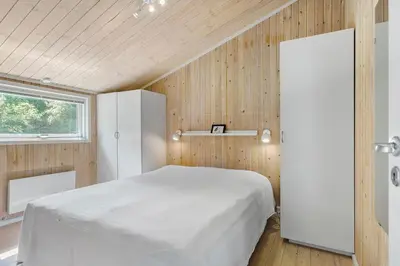 a bedroom with a white bed and wooden walls at Little Fiskerbanke - Lovely, Private, And Family-Friendly Holiday Home in Saltum