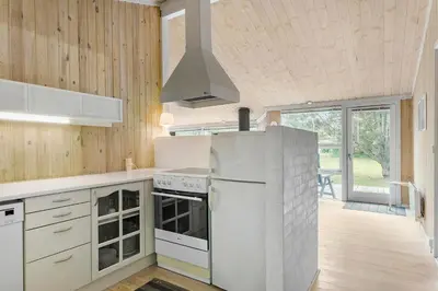 a kitchen with white appliances and wooden walls at Little Fiskerbanke - Lovely, Private, And Family-Friendly Holiday Home in Saltum