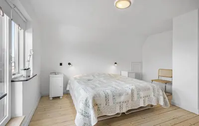 a white bedroom with a bed and a chair at 1 Bedroom Nice Apartment In Thyborøn in Thyborøn